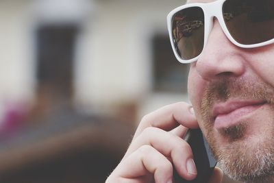 Close-up of man wearing sunglasses using phone outdoors