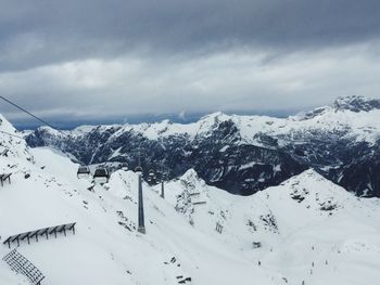 Snow covered mountains against cloudy sky