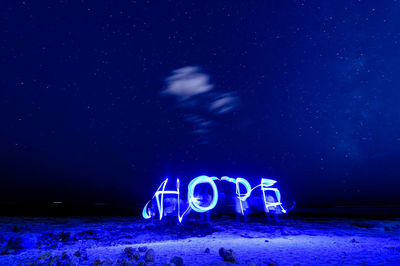 Illuminated hope text made by light painting at beach against star field