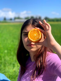 Portrait of woman holding ice cream in field