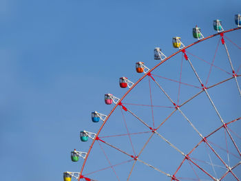 Low angle view of ferris wheel against clear blue sky