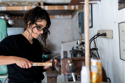 Women works with hammer and anvil in artist studio