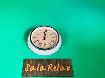 Close-up of wall clock and text on blue background