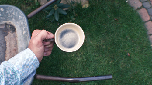 Cropped image of man holding coffee in lawn