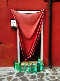 Bottles arranged outside door with red textile