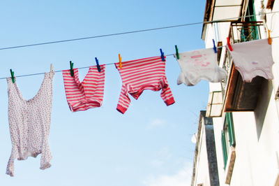 Low angle view of clothes hanging on cable against sky