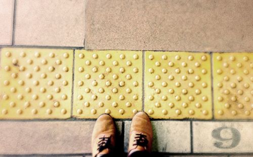 Low section of man standing on yellow shoes