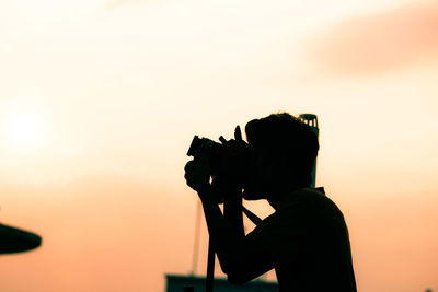 Silhouette of person photographing against clear sky
