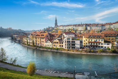 Buildings by river against sky