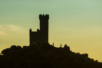 Silhouette built structures against sky during sunset