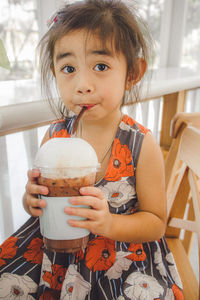 Portrait of cute girl holding ice cream at home