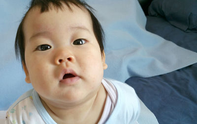 Portrait of cute baby lying on bed