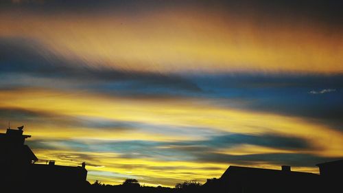 Low angle view of silhouette houses against dramatic sky