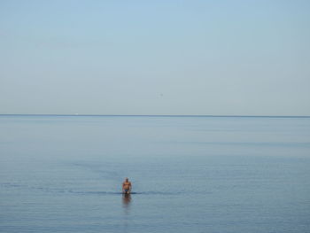 Distant view of man standing in sea against sky