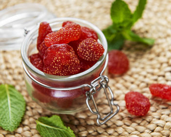 Dried strawberries in jar on a straw mat background