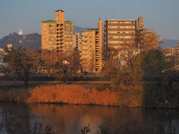 Lake by buildings against sky during autumn