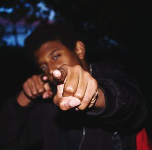 Portrait of young man pointing while standing at dusk