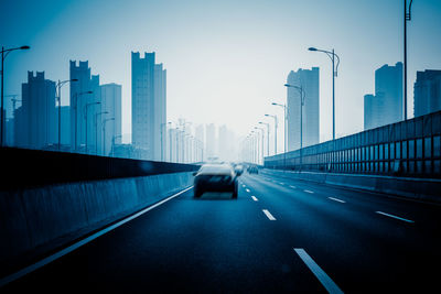 Cars on road amidst buildings in city against sky