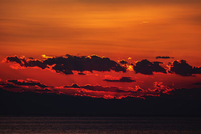 Scenic view of sea against dramatic sky during sunset