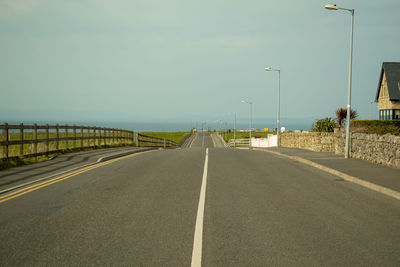 Empty road by street against sky