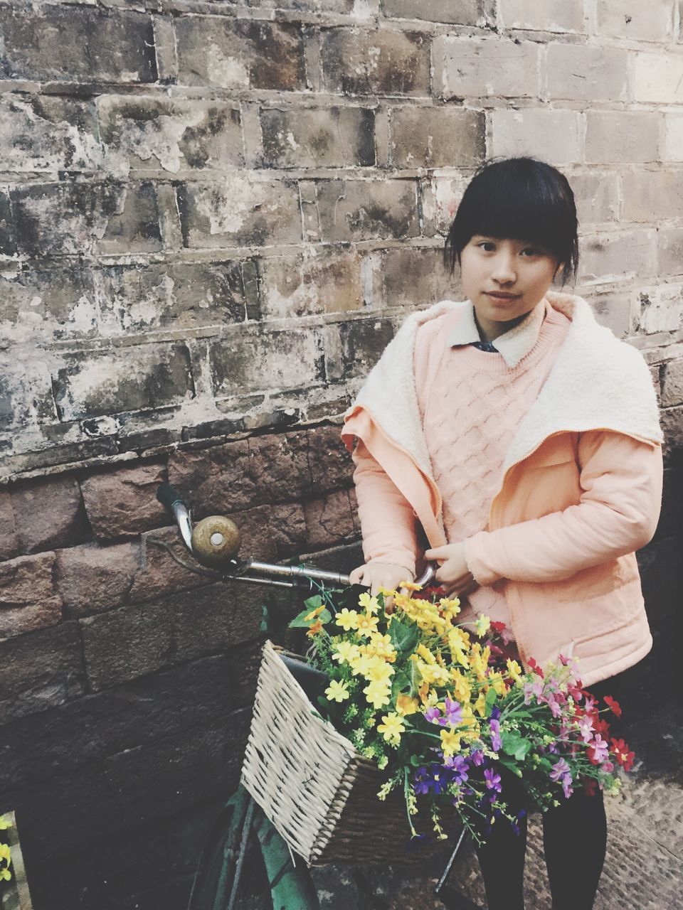 young adult, casual clothing, person, lifestyles, front view, young women, holding, leisure activity, standing, smiling, waist up, portrait, sitting, three quarter length, brick wall, looking at camera, wall - building feature