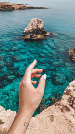 Close-up of hand on rock in sea