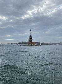 View of building by sea against cloudy sky