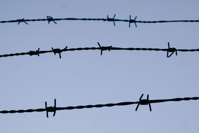 Close-up of barbed wire against sky