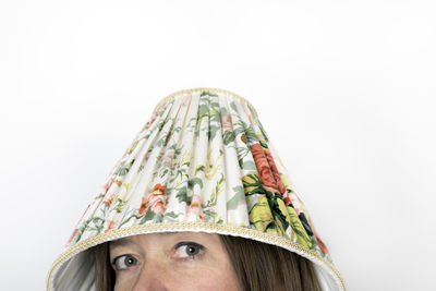 Mature woman with lamp shade on head against white background