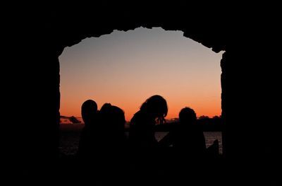 Silhouette people by sea against sky during sunset