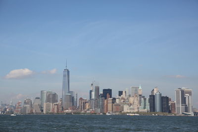 Sea by modern buildings against sky in city