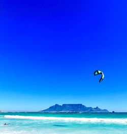 Scenic view of mountain and sea against clear blue sky