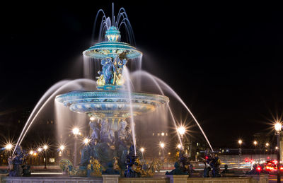 Blurred motion of illuminated fountain in city at night