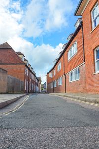 Empty road amidst buildings against sky