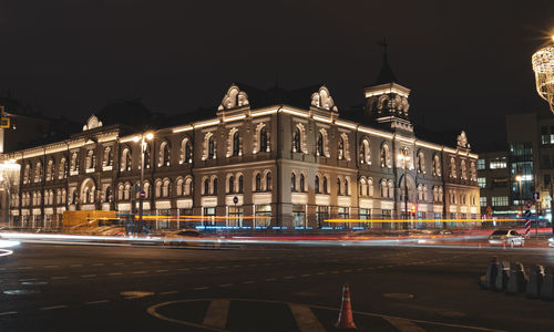 Light trails on road against buildings at night