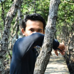 Portrait of young man standing on footpath amidst trees