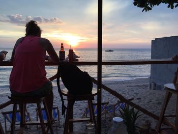 Rear view of woman sitting at outdoors restaurant during sunset