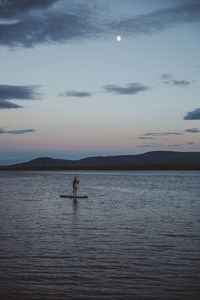 Woman on stand up paddle board at sea at night