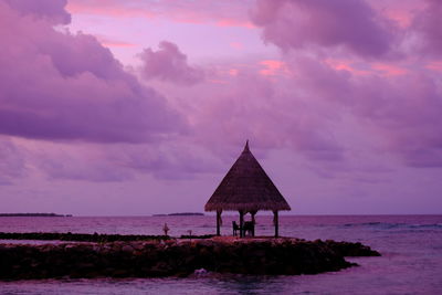 Lifeguard hut by sea against sky during sunset