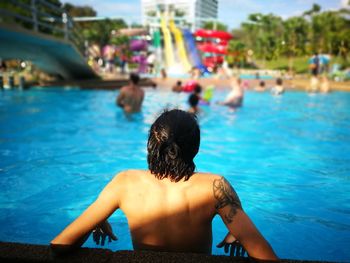 Rear view of shirtless man swimming in pool