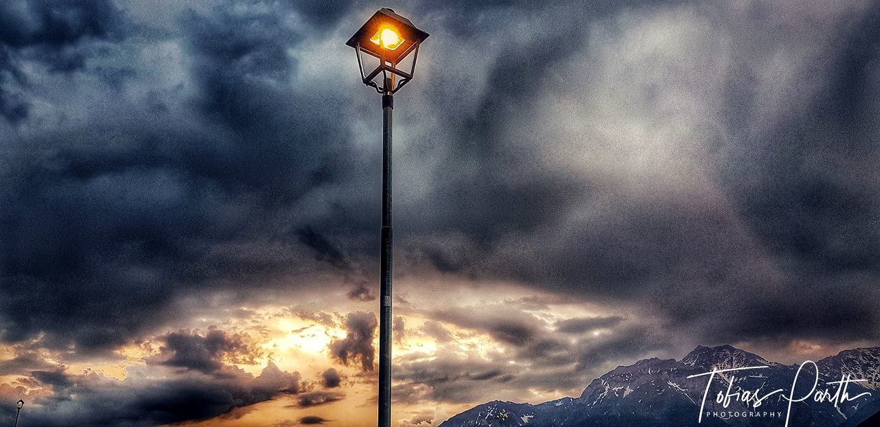 cloud - sky, sky, lighting equipment, street light, beauty in nature, scenics - nature, illuminated, mountain, low angle view, sunset, nature, street, overcast, no people, tranquil scene, outdoors, dusk, storm cloud, dramatic sky, light, ominous