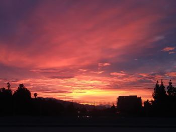 Silhouette of city against dramatic sky during sunset