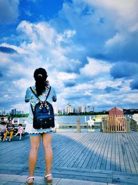 Rear view of woman standing by cityscape against sky