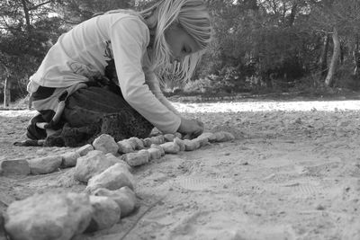 Side view of girls arranging rocks on field