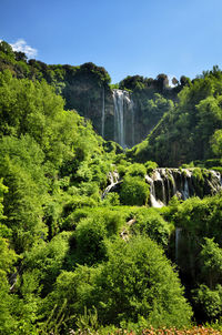 Scenic view of waterfall amidst trees against sky