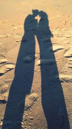 Shadow of man photographing on sand