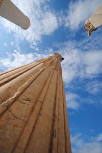 Low angle view of historic columns against cloudy sky