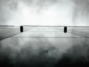 Low angle view of bird perching on cable against sky