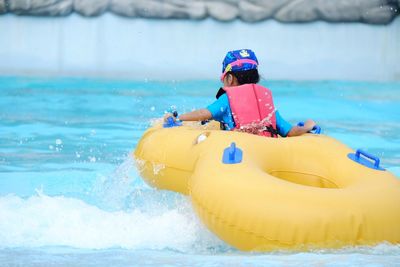 Rear view of girl with inflatable raft in swimming pool
