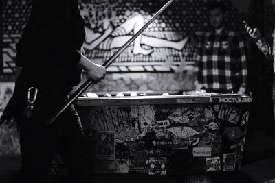 Midsection of person playing snooker in darkroom